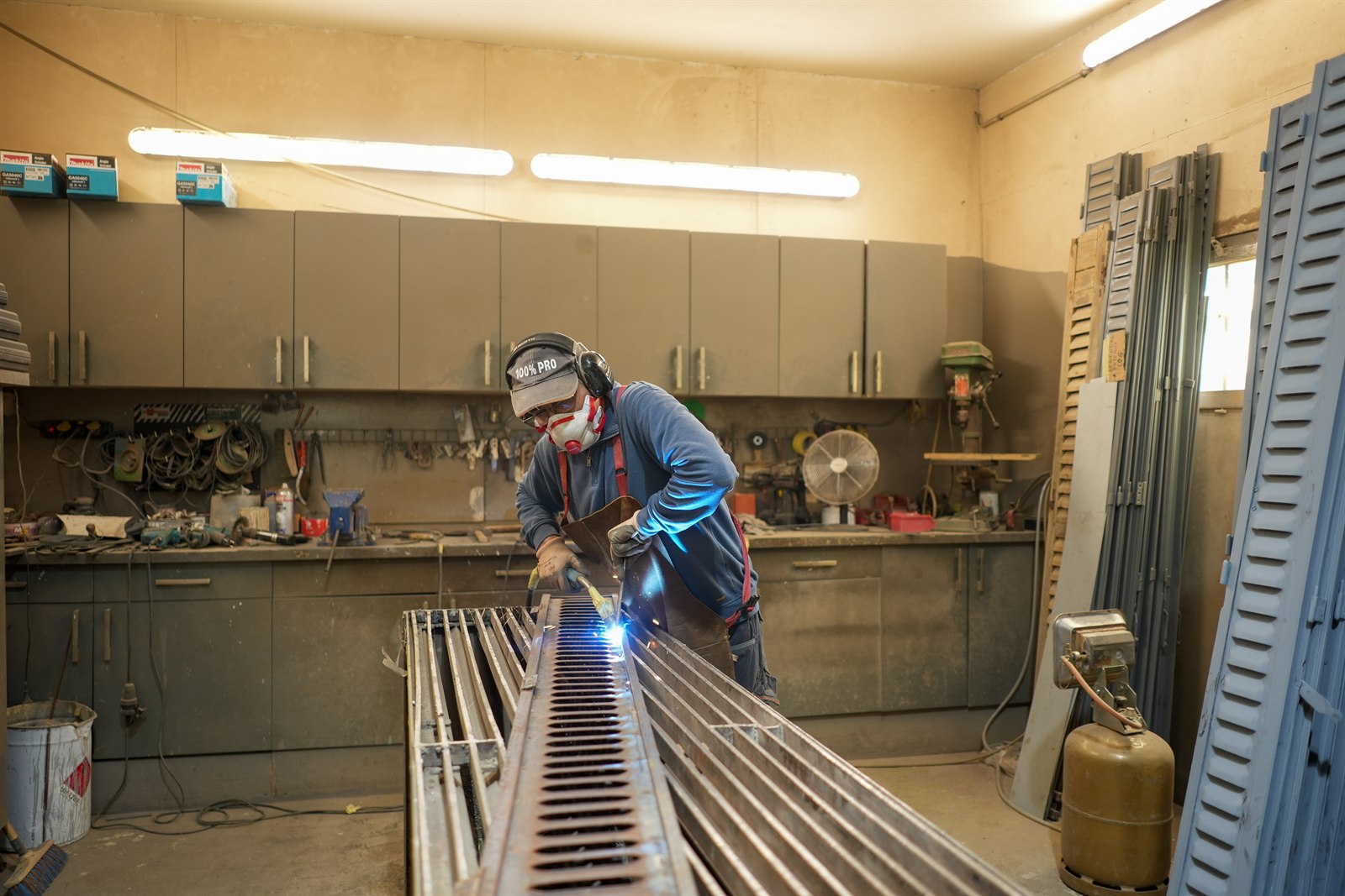 Compagnon Restor'A9 soudant un volet métallique en atelier